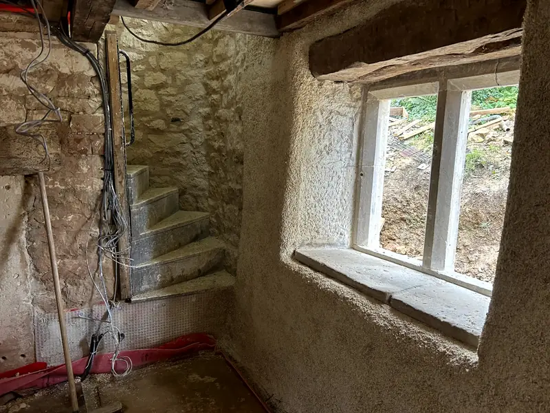 Sprayed hempcrete around a window beside a stone spiral staircase