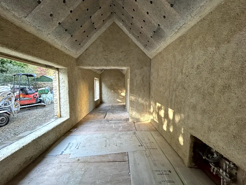 Finished room with sprayed hempcrete walls and a wide window, vaulted ceiling above