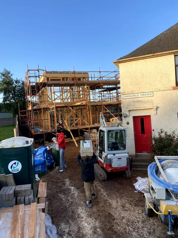 Street view of the site, with the timber frame under scaffold beside a neighbouring house
