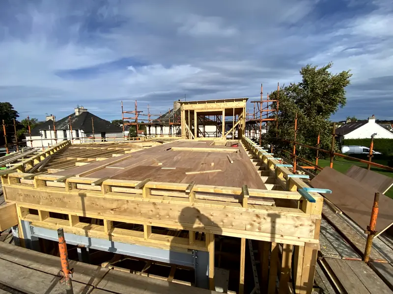 Elevated view across the first-floor deck and timber frame towards the neighbouring houses