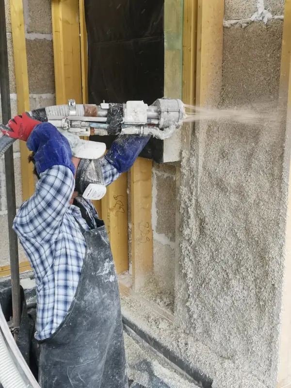 Close-up of hempcrete being sprayed from the nozzle into the timber frame