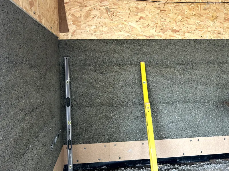 Flat, even cast hempcrete wall with a spirit level and straight-edge leant against it