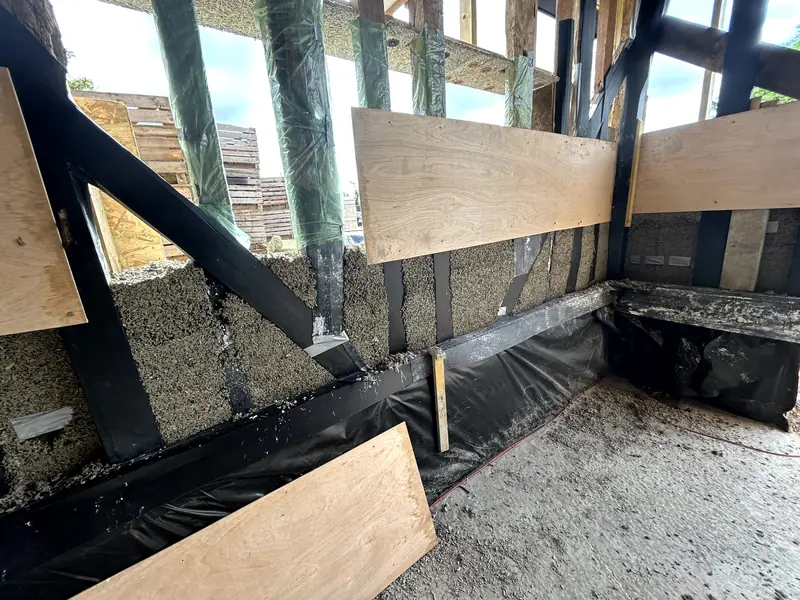 Hempcrete cast into the base of the stud frame, with plywood shuttering and membrane at floor level