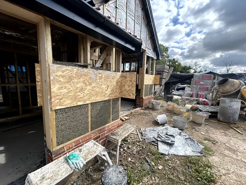 Exterior corner of the barn with OSB shuttering in place over freshly cast hempcrete above the brick plinth