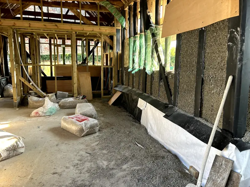 Inside the barn, cast hempcrete along the lower walls with bags of binder and hemp on the floor