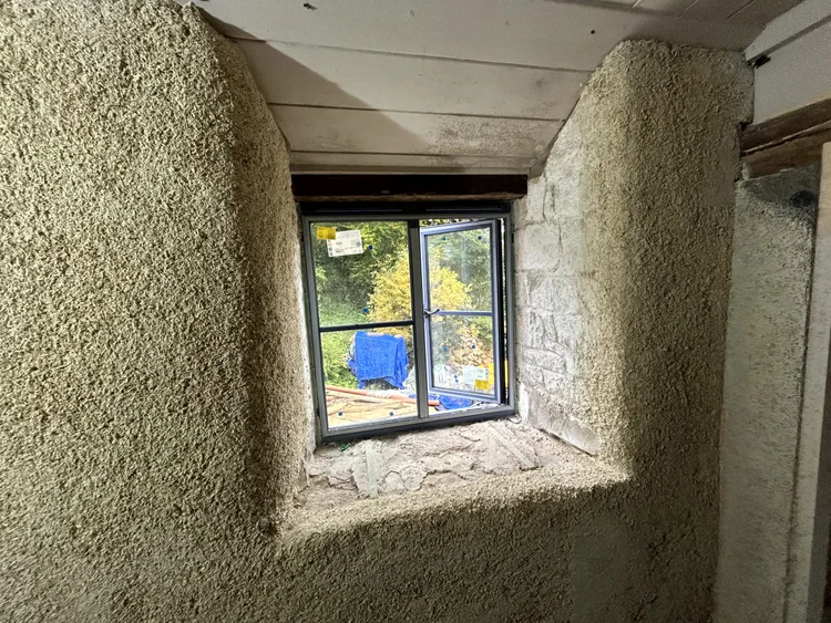 Close-up of hempcrete spray installation around a window reveal